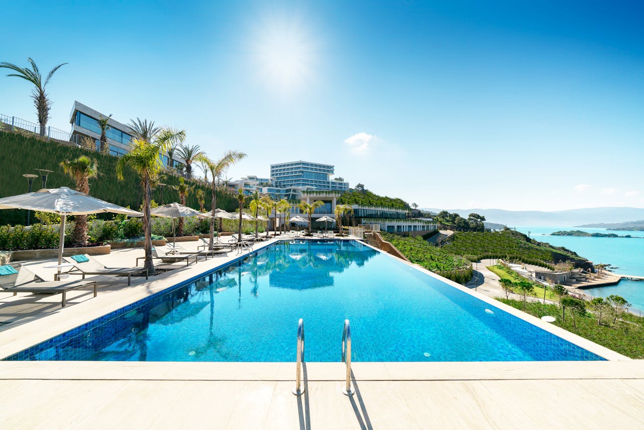 Services A luxurious seaside resort in Bodrum, Turkey, featuring a stunning infinity pool under sunny skies.
