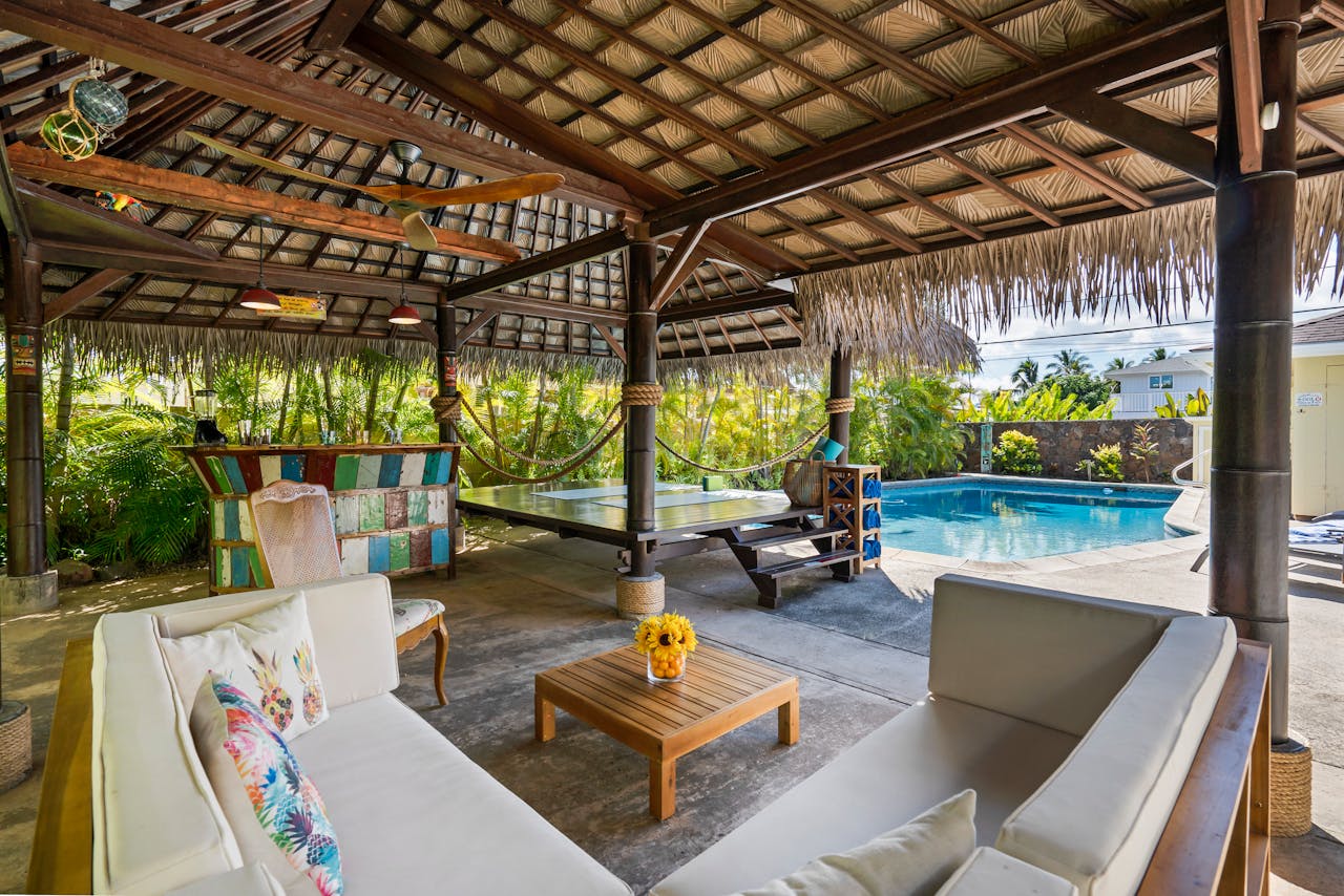 Home Tropical outdoor patio featuring a cabana, seating area, and swimming pool, perfect for luxury relaxation.